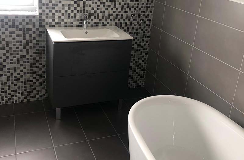 New Bathroom with black and grey tiles and white bath